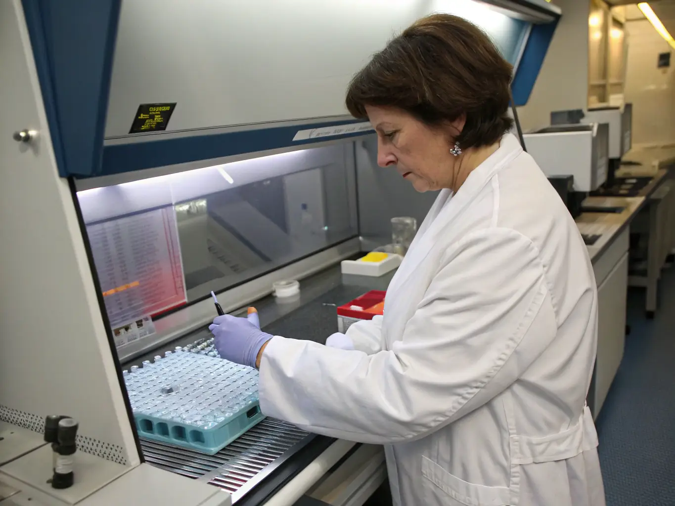 A laboratory technician working with advanced diagnostic equipment, with a computer screen displaying claims data and analysis, highlighting efficient laboratory claims management.